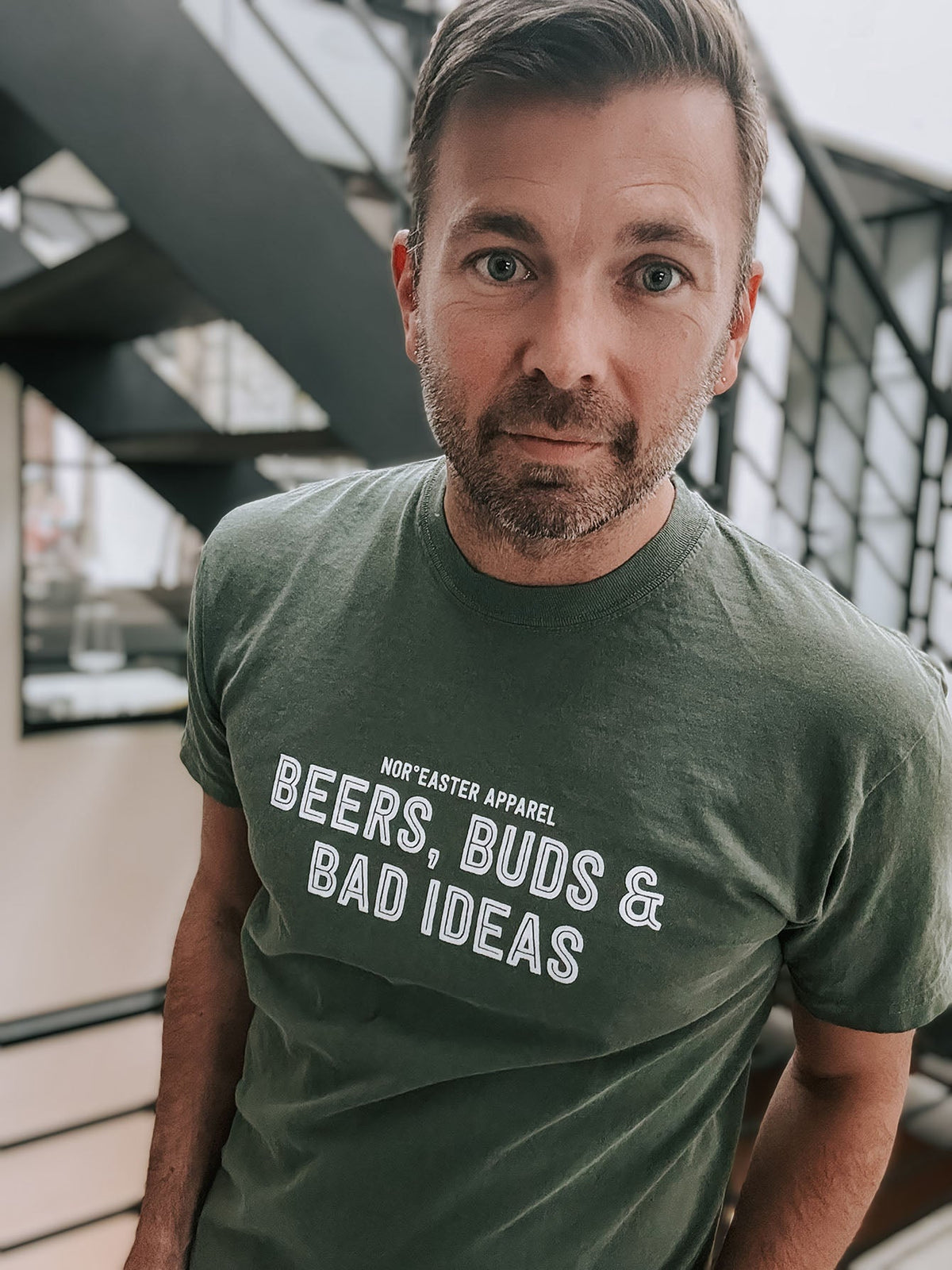 Man wearing a green t-shirt with text standing in an urban setting