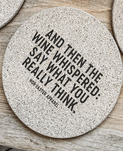 Round stone coaster with humorous text on a wooden surface