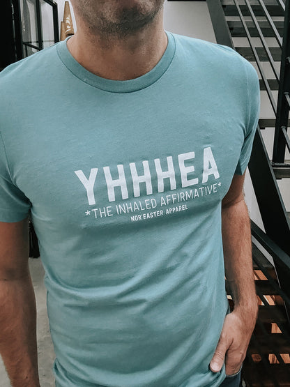Person wearing a teal t-shirt with 'YHHHEA' text design.